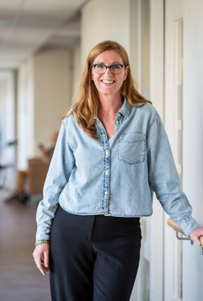 Marieke in de gang bij Anna Ouderenzorg, achterin de gang staat een verzorgende bij een medicijnenkar Marieke is teammanager van het centrum voor herstel en revalidatie bij Anna Ouderenzorg